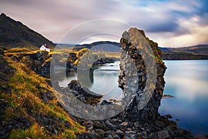 Sea shore in Iceland with cliffs and a small house in the village of Arnarstapi photo