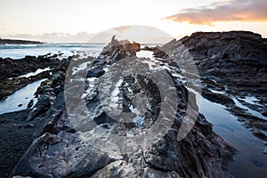 Atlantic sunset over Canary Island. Sea wave breaking against coast rock in sunset time