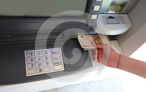 ATM cash machine with keyboard and hand picking up European bank