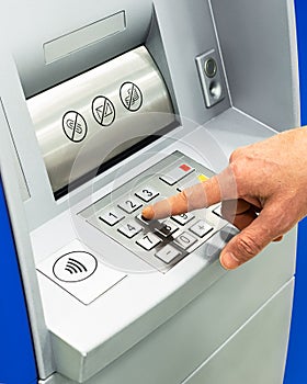 ATM machine close-up. male hand dials a password at an ATM