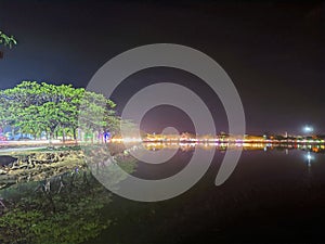 The atmosphere of a city park at night is full of colorful lights and is reflected in the calm water photo