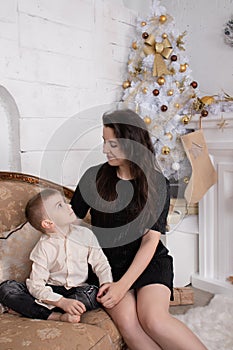 Atmosphere of coming holidays. portrait of happy single mother with her little pleasant boy in white bright room near