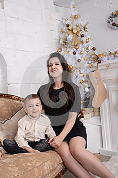 Atmosphere of coming holidays. portrait of happy single mother with her little pleasant boy in white bright room near