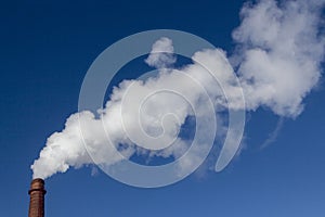 Atmosphere, industry and ecology concept. Thick white smoke comes from the brick industrial factory pipe into the sky.