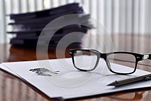 Atmosphere after work, Home office with glasses on paper sheet has document pile is backdrop.