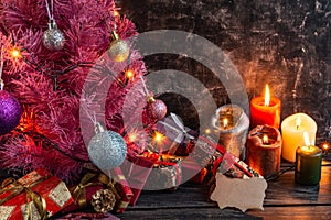 Atmospheric Christmas or New Year composition, pink christmas tree on black background, candles, gifts. Copy space