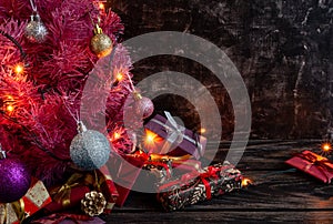 Atmospheric Christmas or New Year composition, pink christmas tree on black background, gifts. Copy space