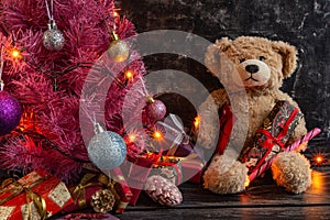 Atmospheric Christmas or New Year composition, pink christmas tree on black background, teddy bear, gifts. Copy space