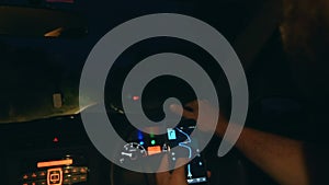 Atmospheric close-up shot of man driving a car at night and holding smartphone following GPS navigation app map route.