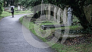 Woman walking through the rain in a graveyard