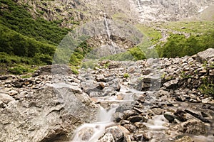 Atmospheric landscape with big stones in mountain river. Powerful water stream among boulders in mountain creek