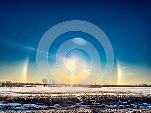 Atmospheric optical phenomenon sun dogs in the morning across a snow field.