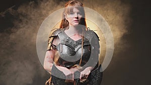 Atmospheric portrait of a scandinavian female barbarian with axe in dark and smokey background