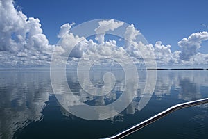 Atmospheric sky art image. White Cumulonimbus cloud in blue sky with ocean water reflections. Australia