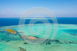 Atoll and blue sea, view from above. Seascape by day. Small islands on the reefs