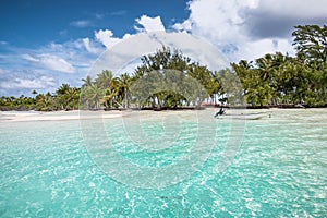 Atoll of Fakarava Island with small anchored boat at beautiful palm tree beach in French Polynesia.