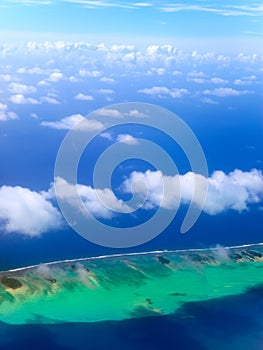 The atoll in ocean through clouds. Aerial view.Landscape in a sunny day