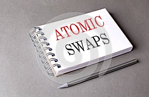 ATOMIC SWAPS text on notebook on grey background