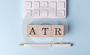 ATR on wooden cubes with pen and calculator, financial concept