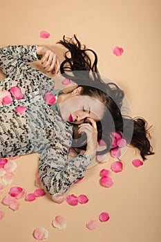 Atractive brunette girl lying on beige background