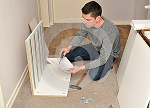 Atractive male assembling a cupboard - reading instructions