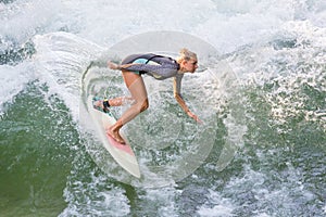 Atractive sporty girl in neoprene shorty wave surfing.