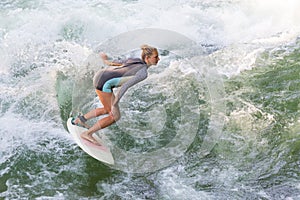 Atractive sporty girl surfing on famous artificial river wave in Englischer garten, Munich, Germany.