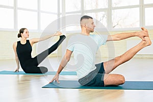 Atractive yoga couple , man and woman, practice exercises in a training hall