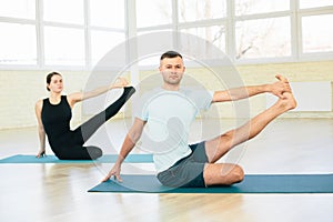 Atractive yoga couple , man and woman, practice exercises in a training hall