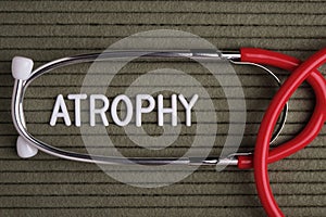 Atrophy - text from white letters on  green background with  stethoscope, medical concept diagnostics