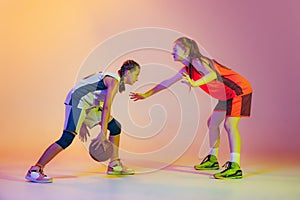 Attack and defense. Female basketball players, young girls, teen in action with basketball ball isolated on neoned