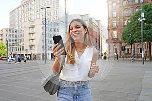 Attactive business woman watching her smartphone walking in the city Manchester, UK