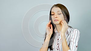 Attactive Smart Business Woman Listens Music Using Headphones in the Studio on Grey Background.