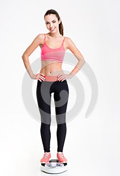 Attactive smiling young fitness woman standing on weighing scale