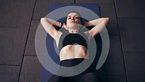 Attarctive brunette in black sportswear doing body bending abs exercises to achieve healthy strong muscles, body, look