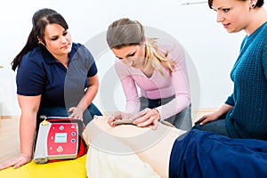 Attendees of first aid class learning how to use defibrillator