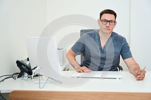 Attending physician sits at his desk at his workplace