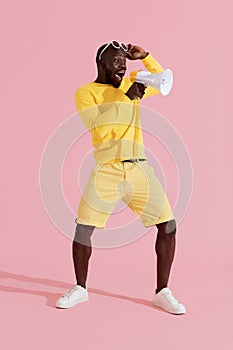 Attention! Black man shouting in megaphone on pink background