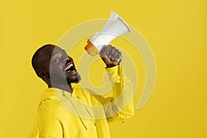 Attention! Black man shouting in megaphone on yellow background