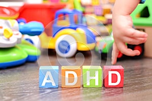 Attention Deficit Hyperactivity Disorder or ADHD concept with toddler hand touching colored cubes against toys photo