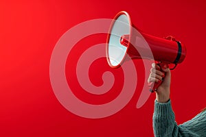 Attention grabbing image Hand holds megaphone against red background