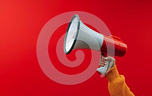 Attention grabbing image Hand holds megaphone against red background