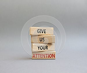Attention symbol. Concept word Give us your attention on wooden blocks. Beautiful grey background. Business and Give us your
