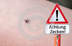 Attention ticks Warning sign with a tick on the arm in german