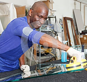 attentive African American glazier choosing glass for cutting in workshop