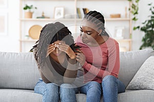 Attentive african american lady comforting her upset friend photo