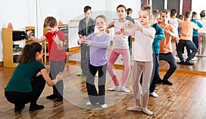 Attentive boys and girls rehearsing ballet dance in studio