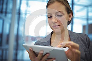 Attentive businesswoman using digital tablet in corridor