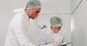 Attentive butchers discussing over clipboard