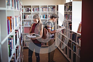 Attentive classmates reading book in library